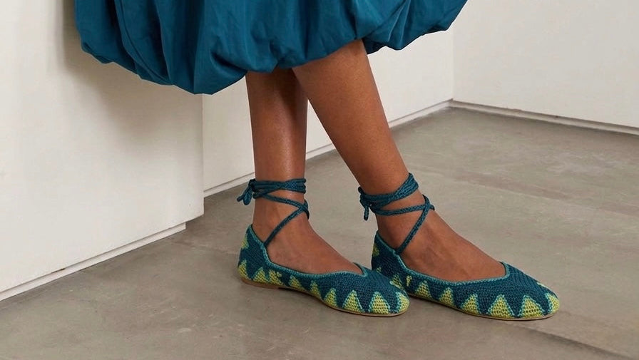 Person wearing a blue dress with green shoes and holding a brown clutch.