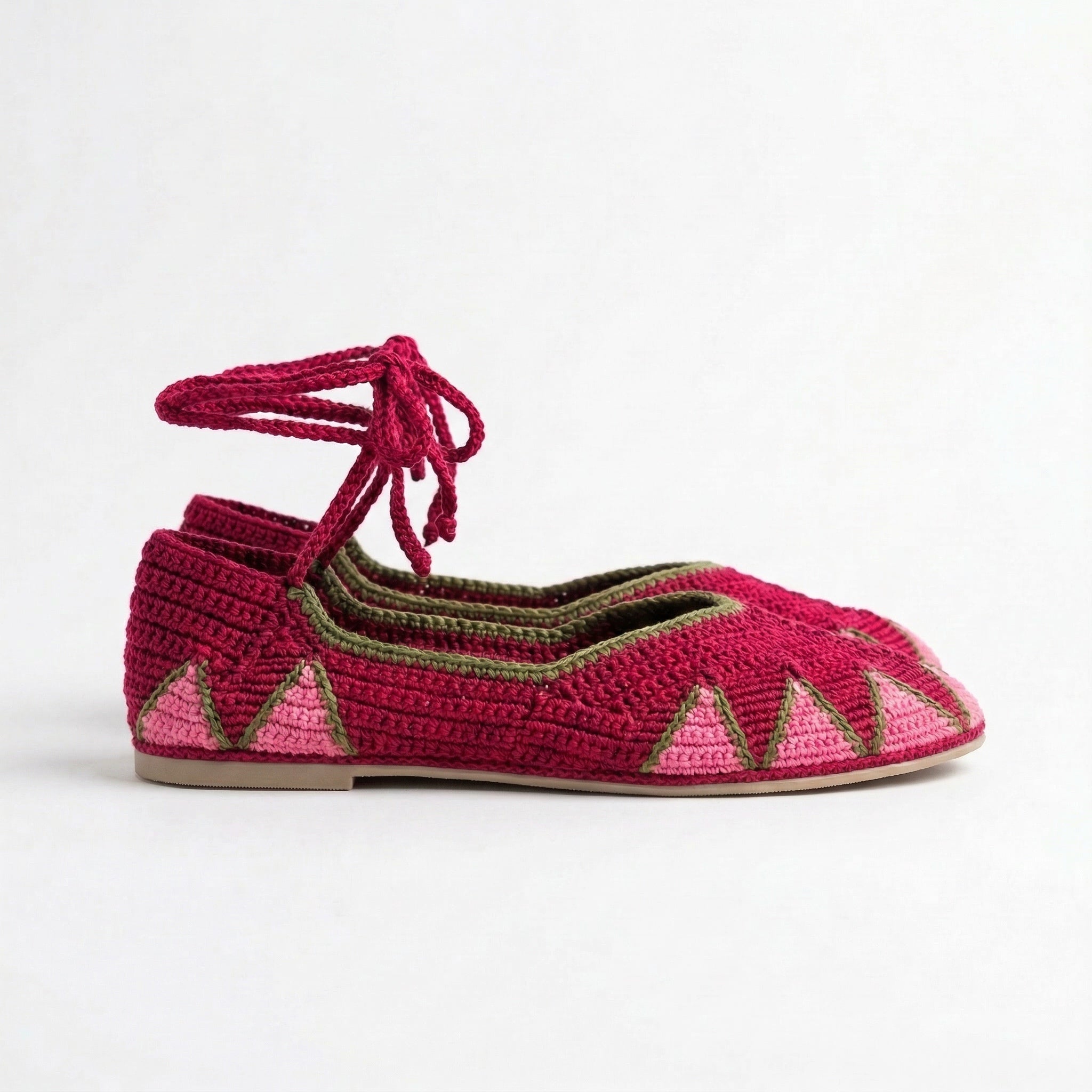 Pair of pink crochet shoes with geometric patterns on a white background